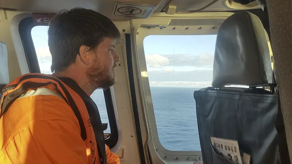 Mann schaut während der Aufnahme für Trident Energy aus dem Helikopterfenster