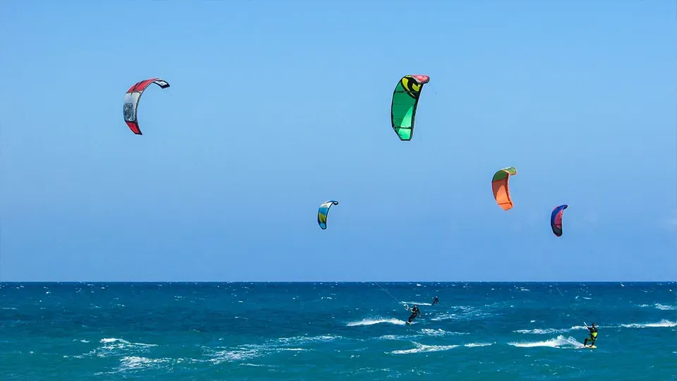 A group of people are flying kites over the ocean.