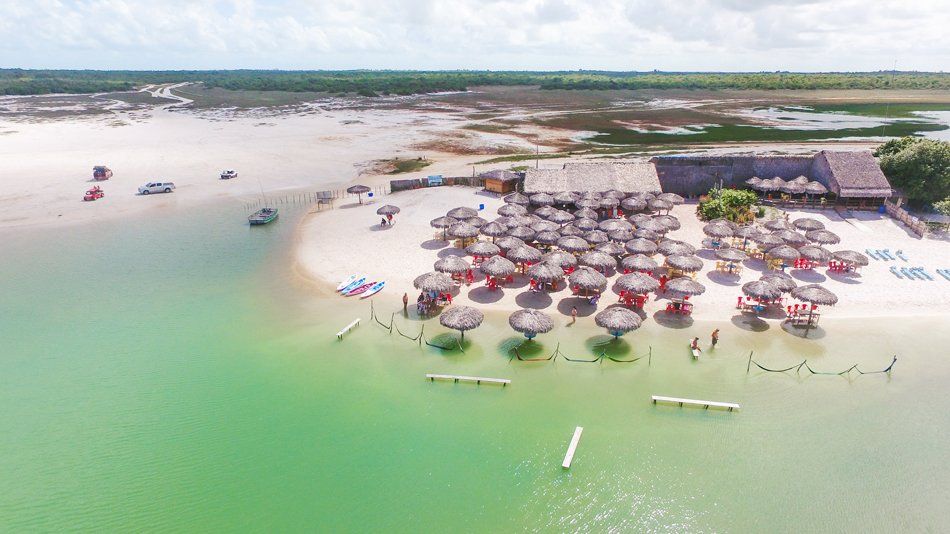 An aerial view of a beach with umbrellas and chairs in the water.