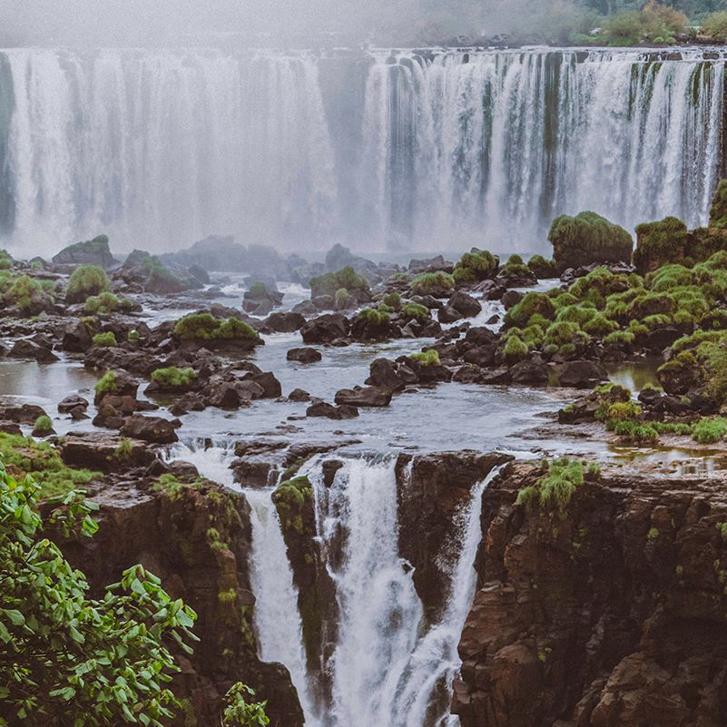 A large waterfall is surrounded by rocks and trees