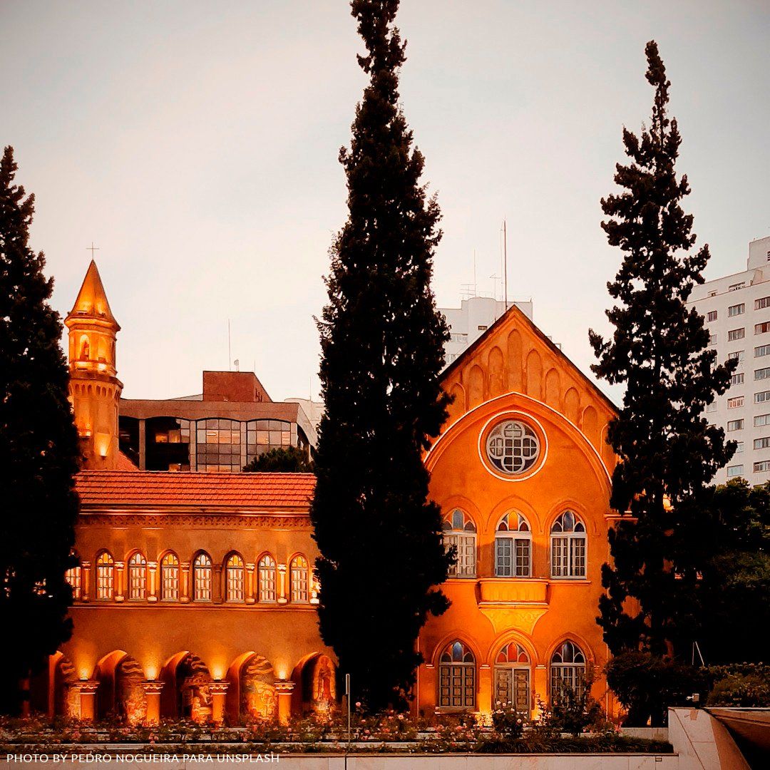 A lighted church in Avenida Paulista, São Paulo A large orange building with trees in front of it