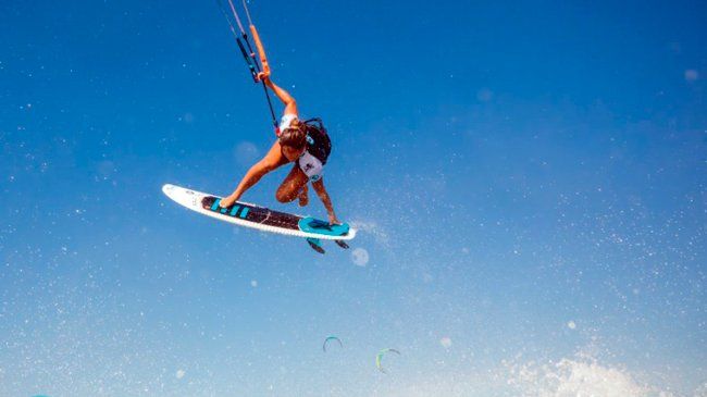 La atleta de kitesurf Mikaili Sol A woman is doing a trick on a surfboard in the air.