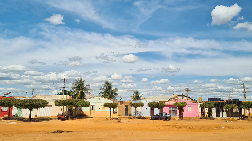 A row of houses with palm trees in front of them under a cloudy sky.