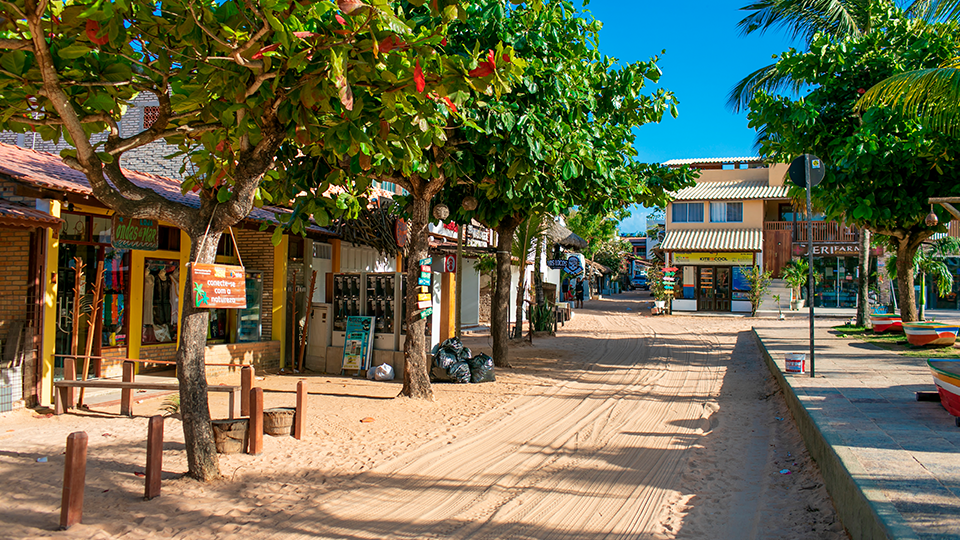 Un camino de tierra con casas de madera alrededor A row of shops are lined up on a dirt road in a small town.