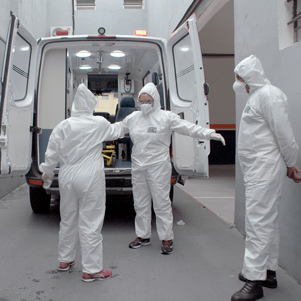 Remote post-production Three people in protective suits are standing in front of an ambulance