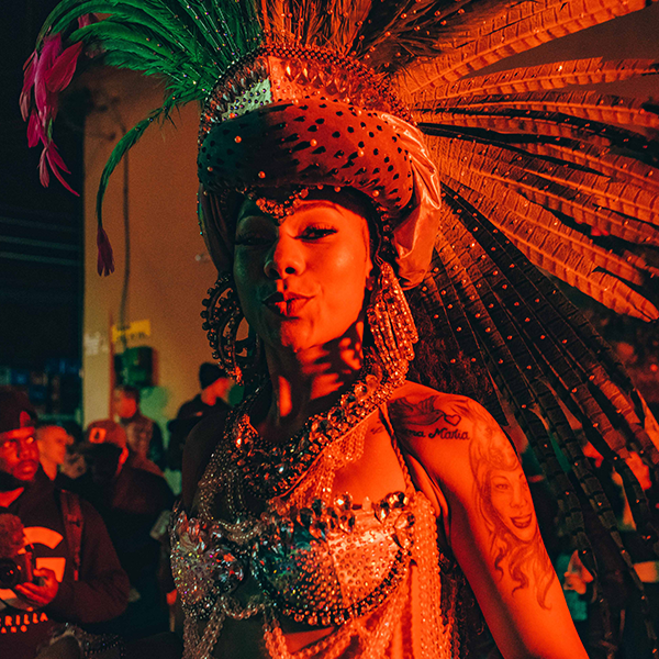 A woman in a carnival costume is standing in front of a crowd.