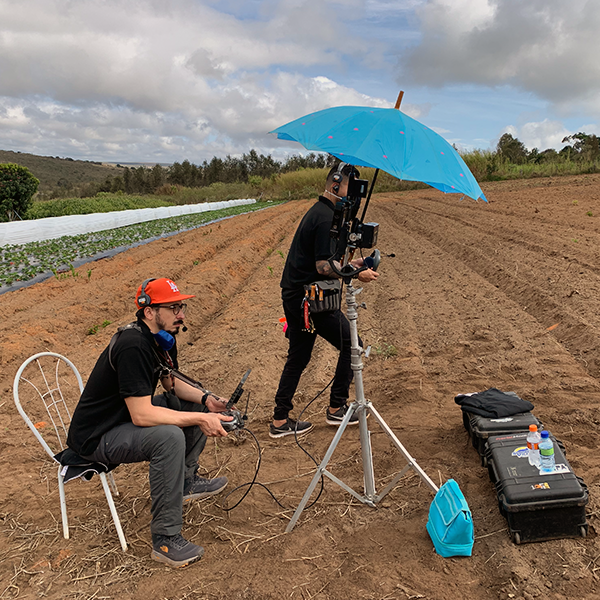 Story Production crew on location at a coffee farm Story Crew are standing in a field with a blue umbrella.