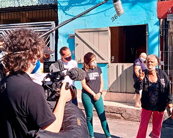 A man is taking a picture of a group of people standing in front of a blue building.