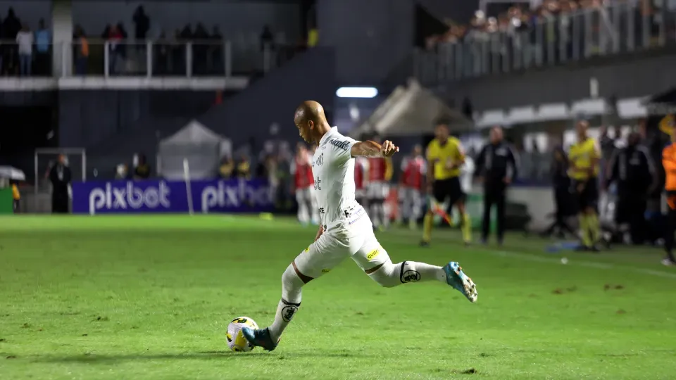 A soccer player is kicking a soccer ball on a field.