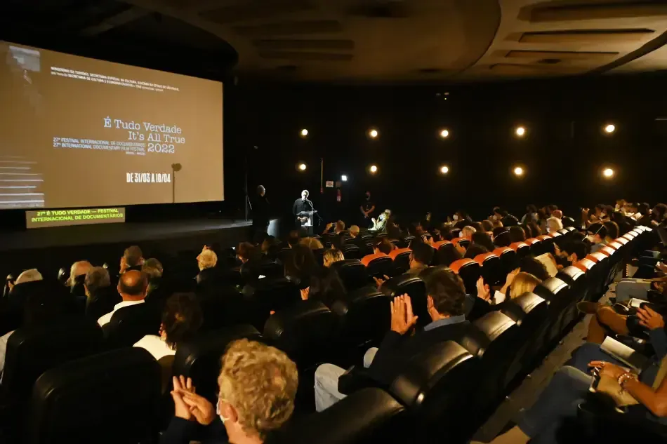 A large group of people are sitting in a theater watching a movie