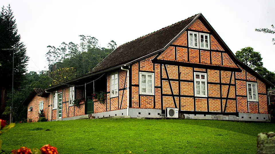 A large brick house sits on top of a lush green hillside