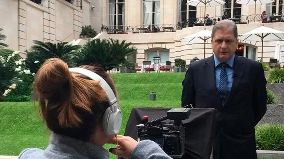 A man in a suit is being interviewed by a woman wearing headphones.