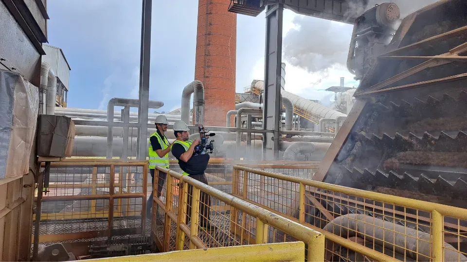 A man is taking a picture of a factory with a camera.
