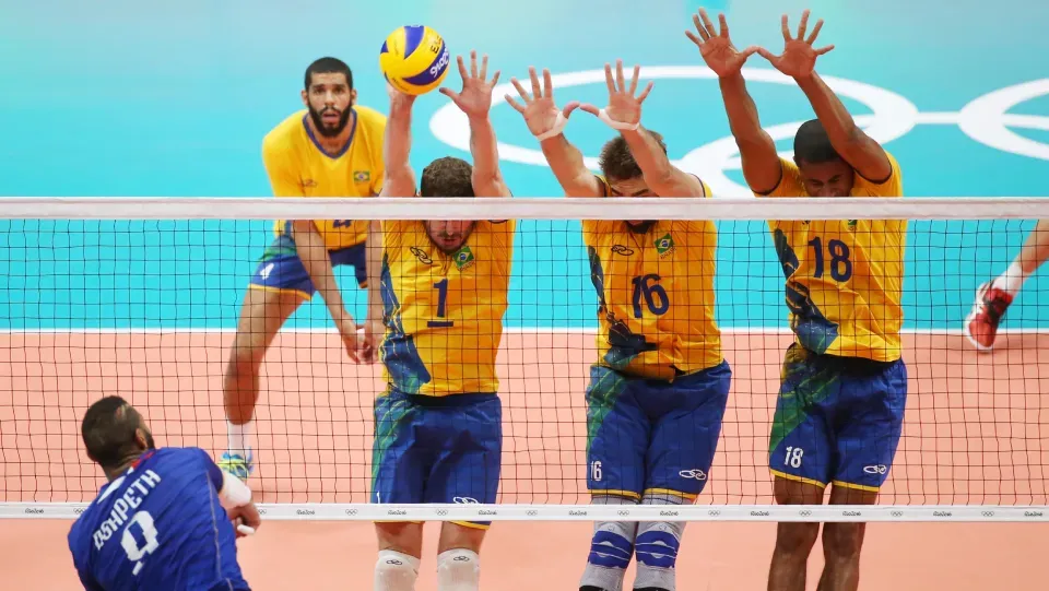 A group of men are playing volleyball on a court.