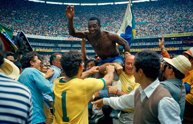 A group of men are carrying a shirtless man on their shoulders in a stadium.
