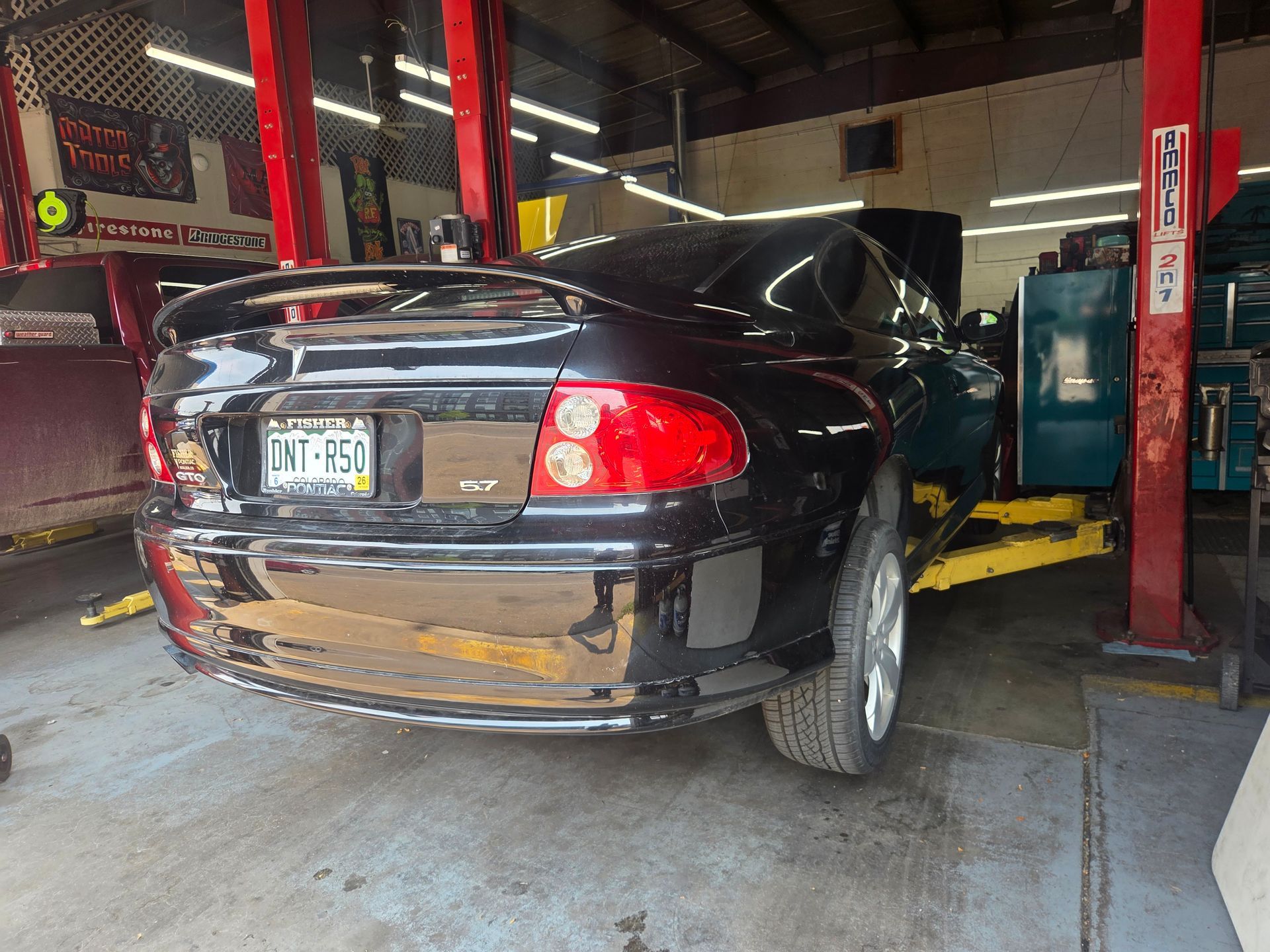 Black sedan on a car wash conveyor inside an industrial garage