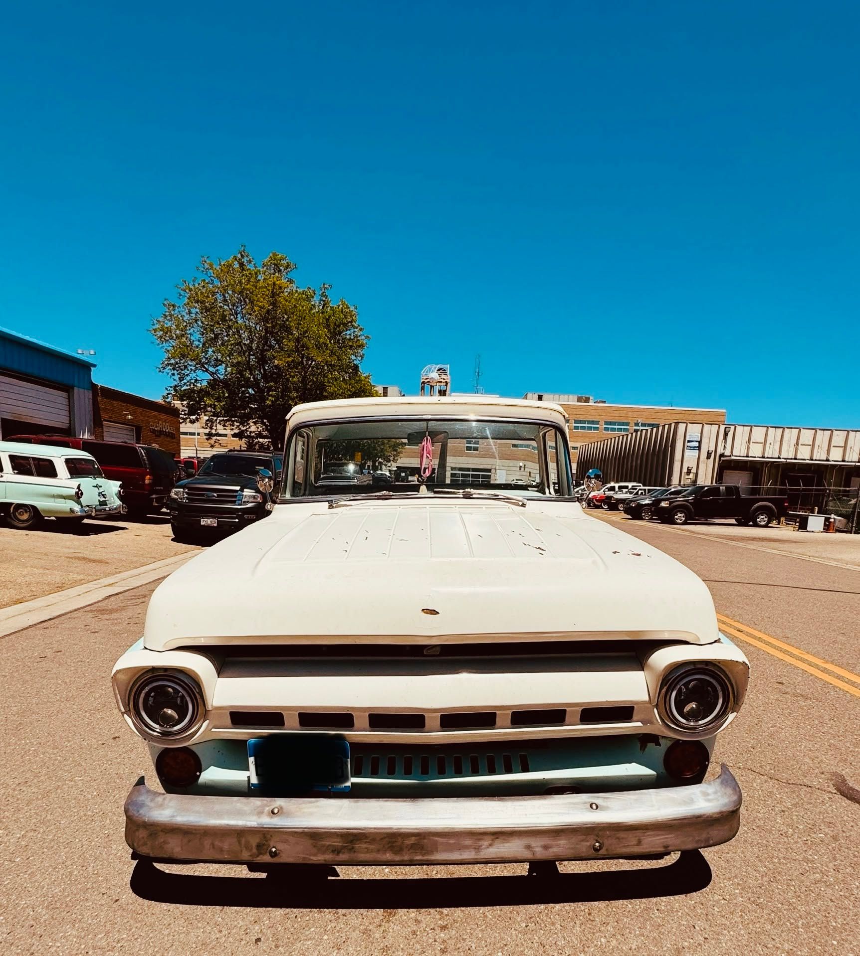 Front view of a vintage white pickup truck parked on a sunny street