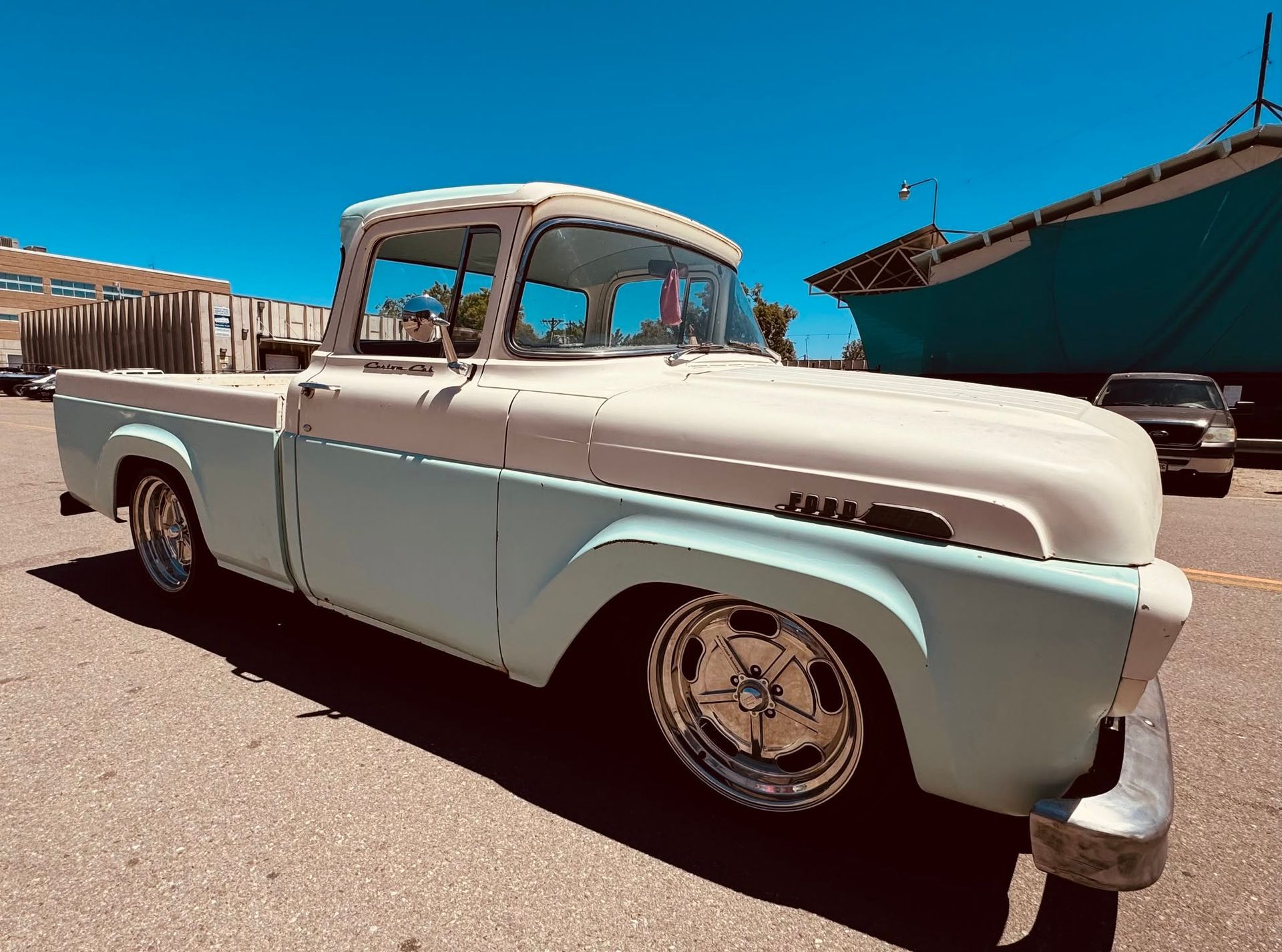 White vintage pickup truck parked in a sunny desert lot under a blue sky