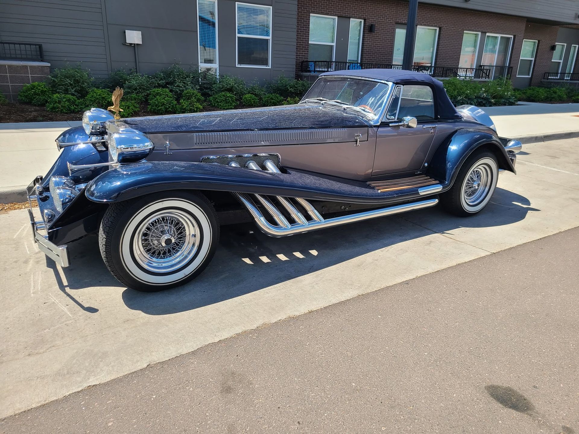 Vintage blue convertible parked on a street in front of a building