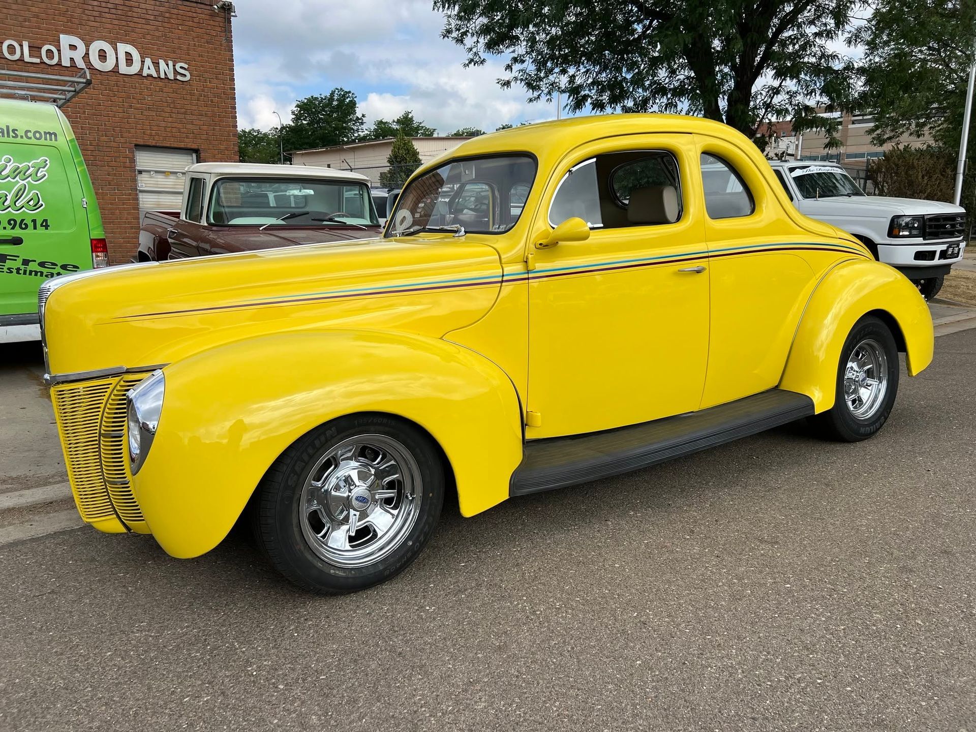 Bright yellow vintage coupe parked outdoors on a street, side view