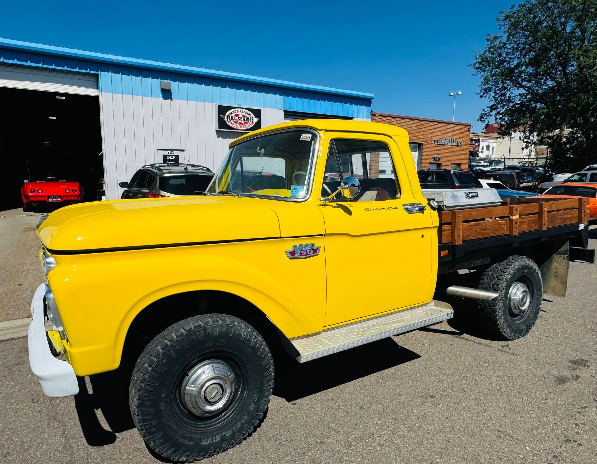Yellow vintage pickup truck parked outdoors on a sunny lot with a wooden cargo bed.