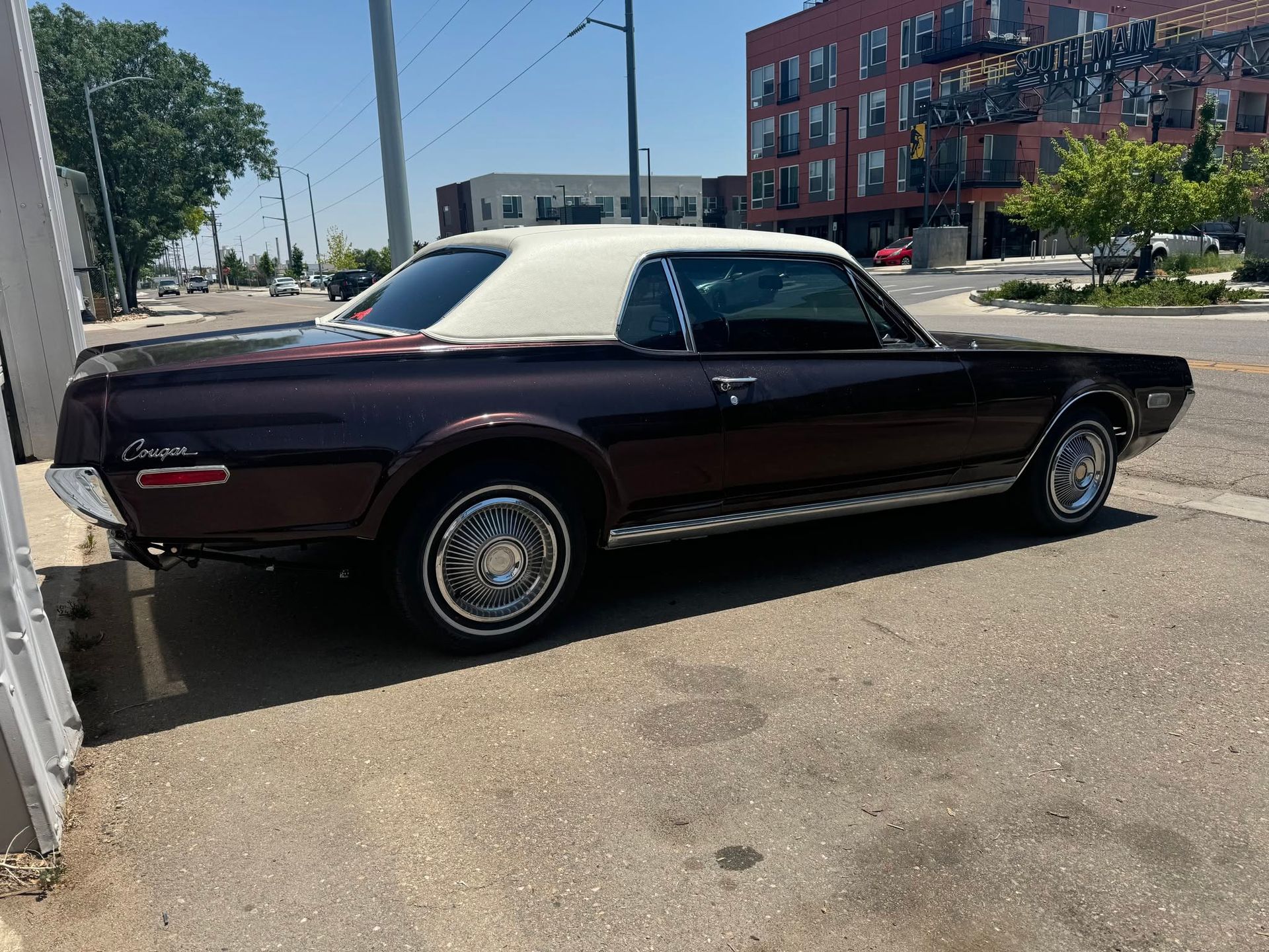 Maroon classic coupe parked beside a building on a sunny street