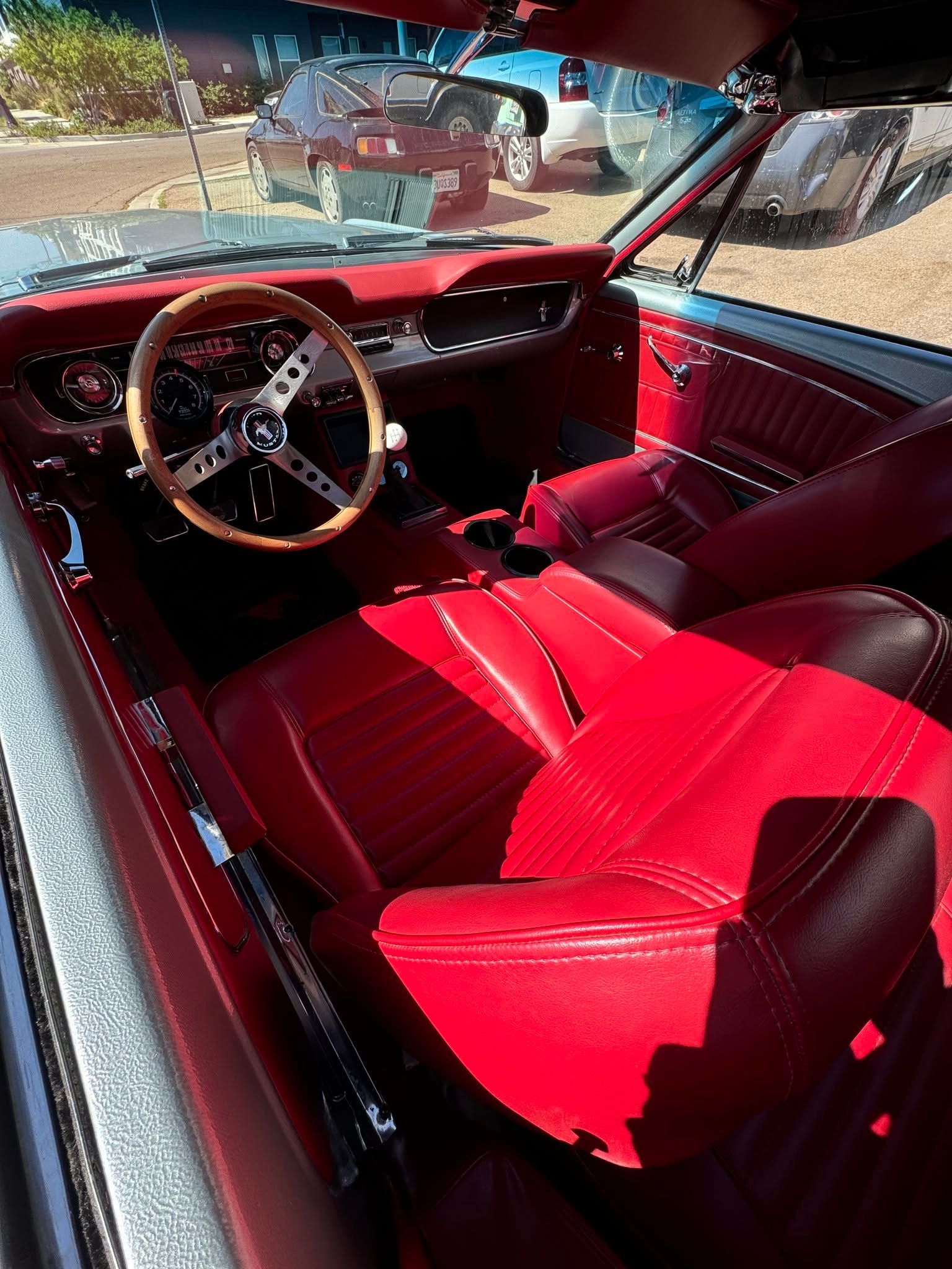 Red car interior with bright red seats and dashboard, viewed from the driver’s side.