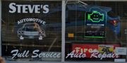 Steve’s Automotive storefront with “Full Service” and “Fire Auto Repair” signs and a neon engine light sign