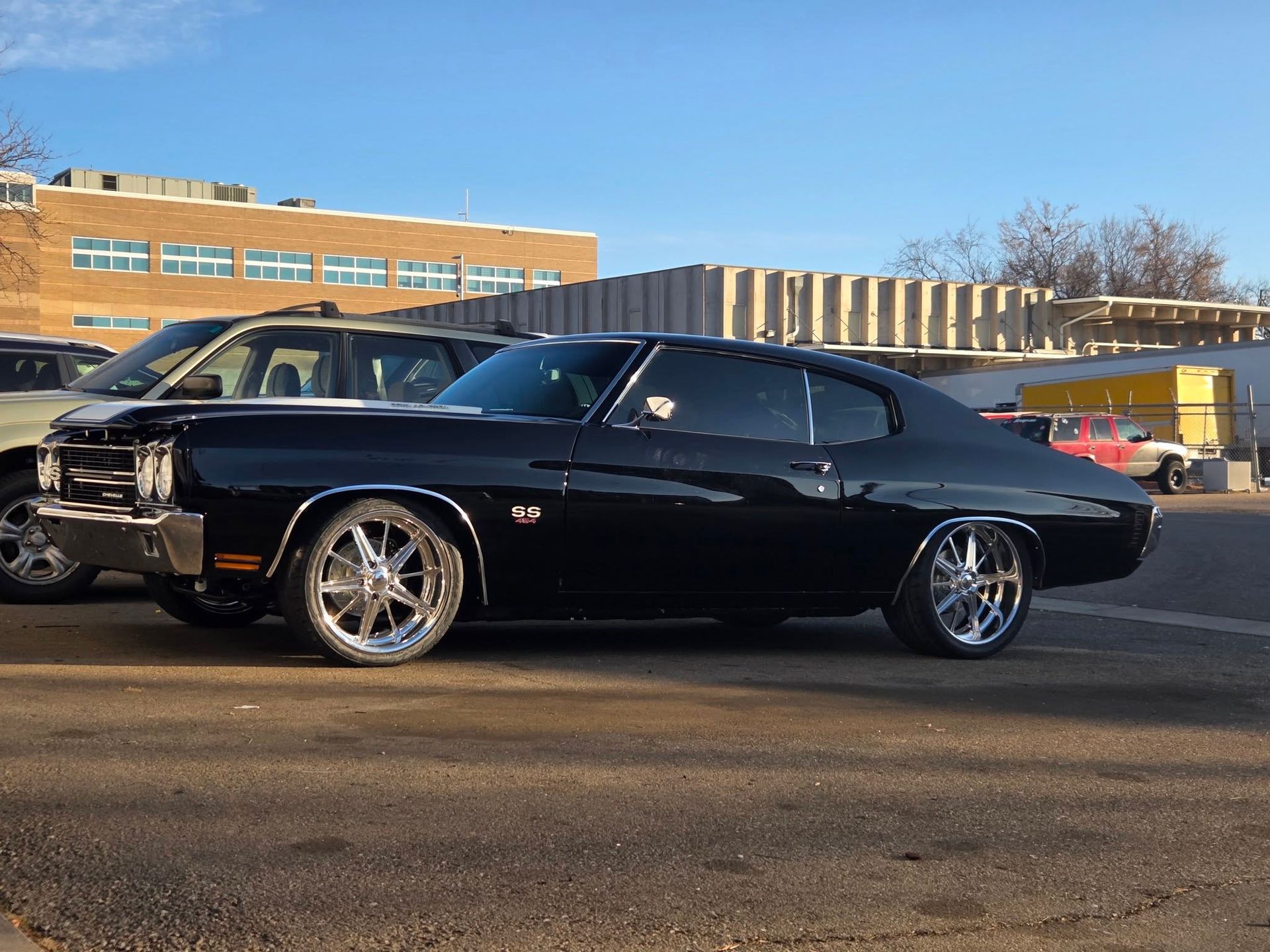 Black classic car parked in a lot with a building in the background