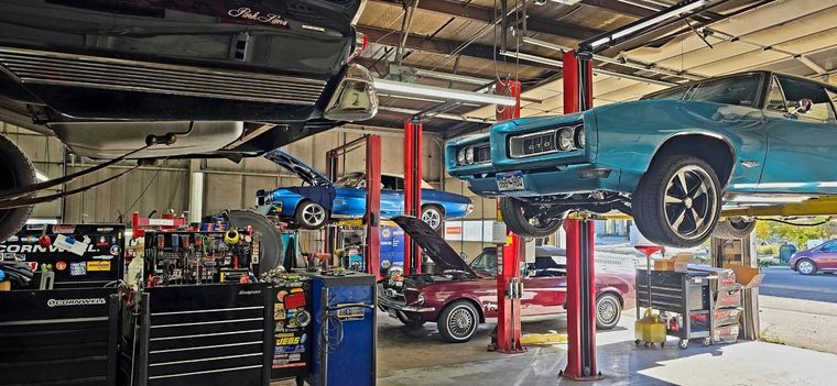 Auto repair shop with a blue car lifted on a red hoist and mechanics’ tools below