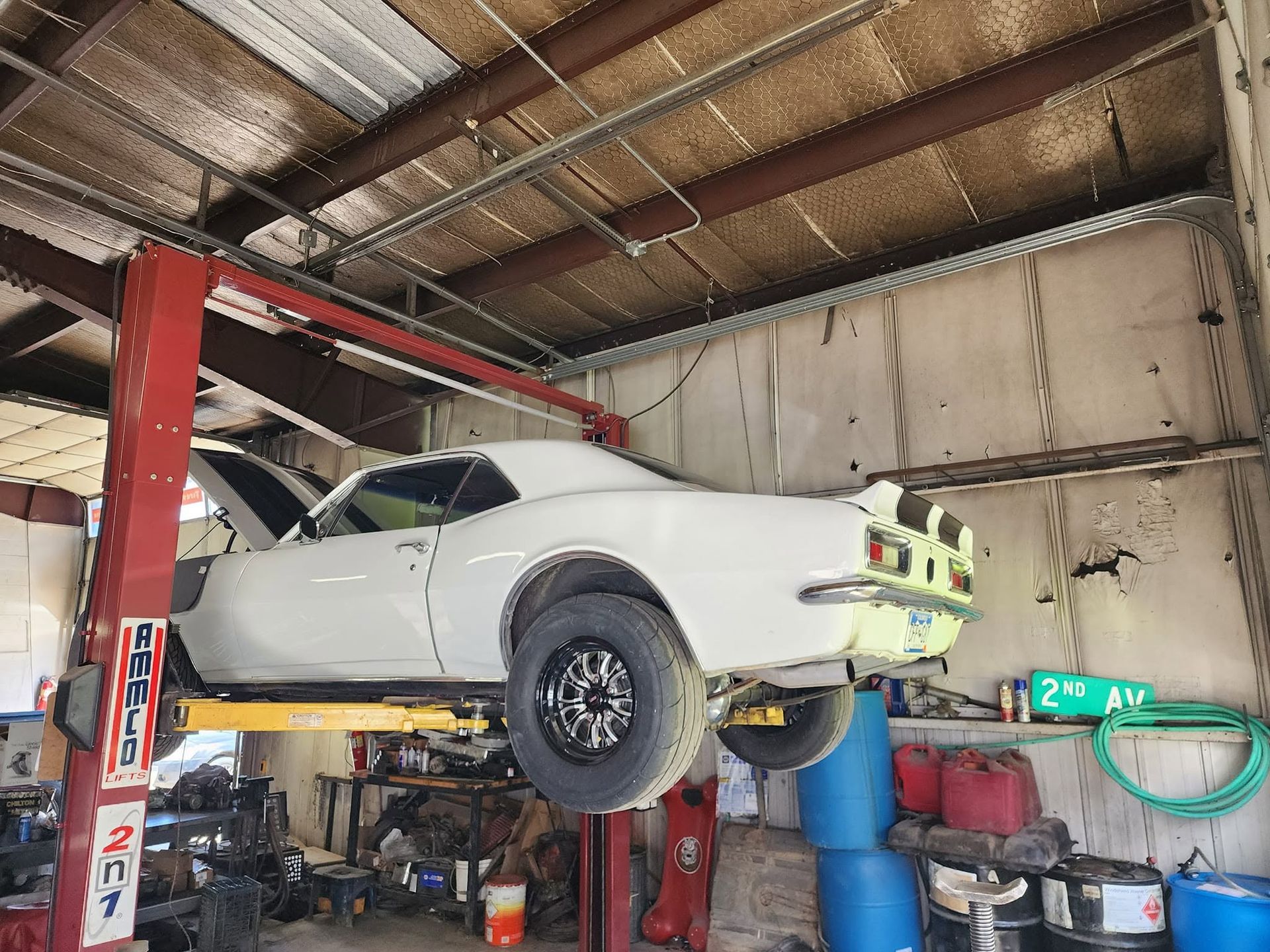 White classic car raised on a red vehicle lift inside an auto repair shop