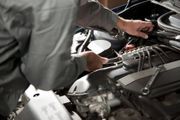 Mechanic inspecting a car engine with tools in a garage