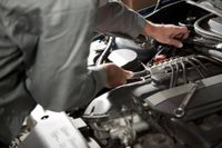 Mechanic inspecting a car engine with tools in a garage