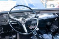 Classic car dashboard with chrome steering wheel, radio, and gauges in a bright interior