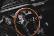 Vintage car dashboard with wooden steering wheel and classic gauges, close-up interior view