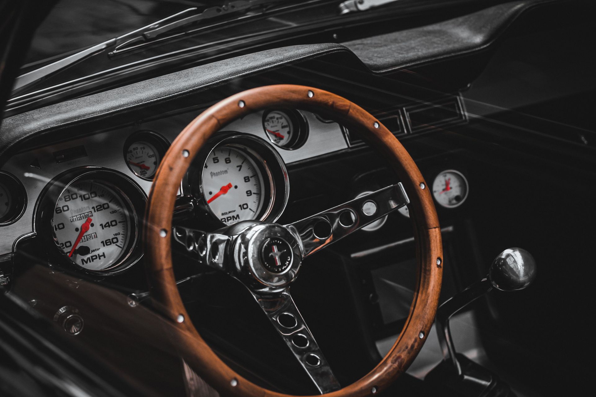 Vintage car dashboard with wooden steering wheel and classic gauges, close-up interior view