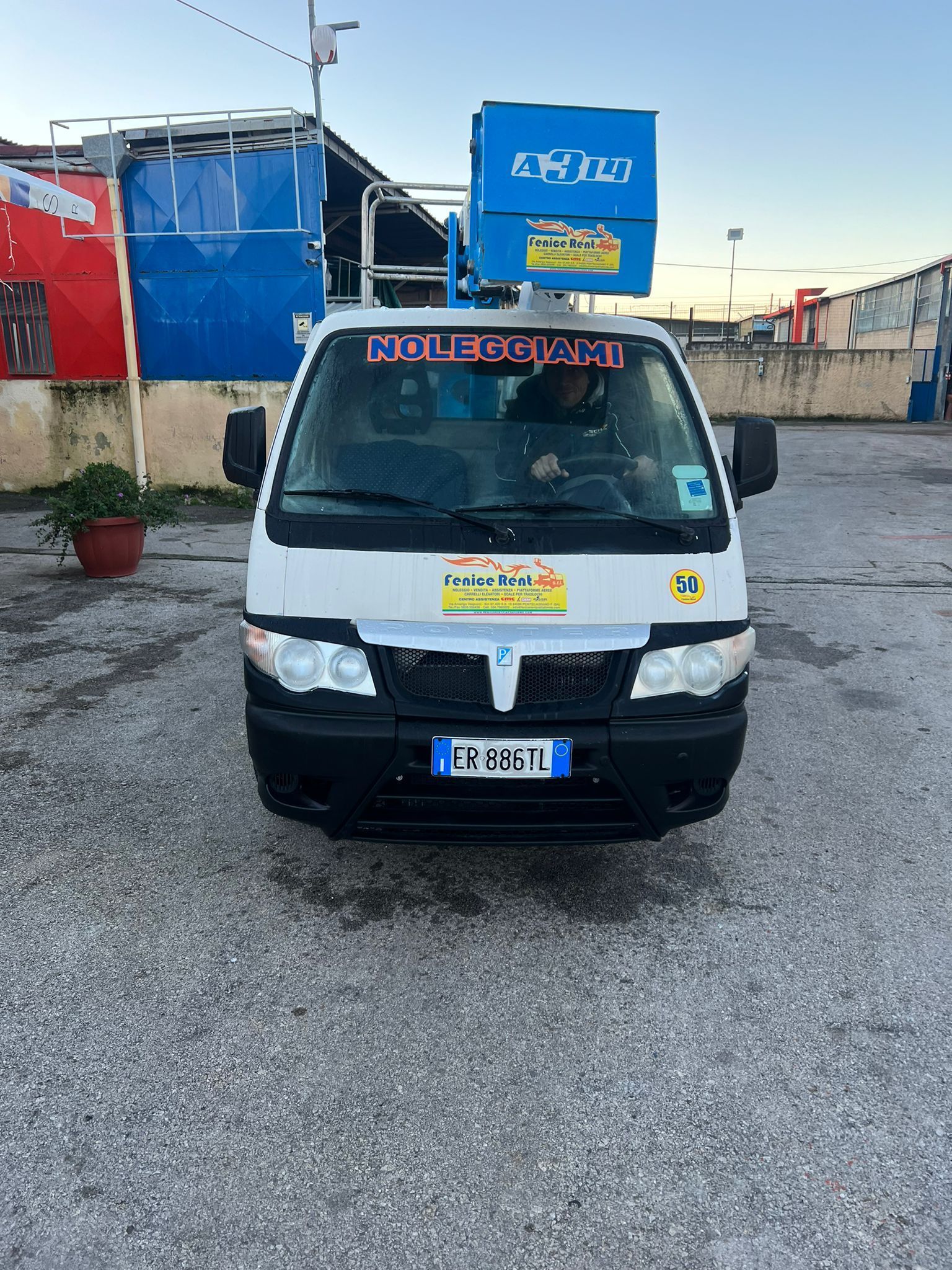 Camion bianco con sollevatore blu, parcheggiato in un parcheggio; sulla parte anteriore è visibile la scritta 