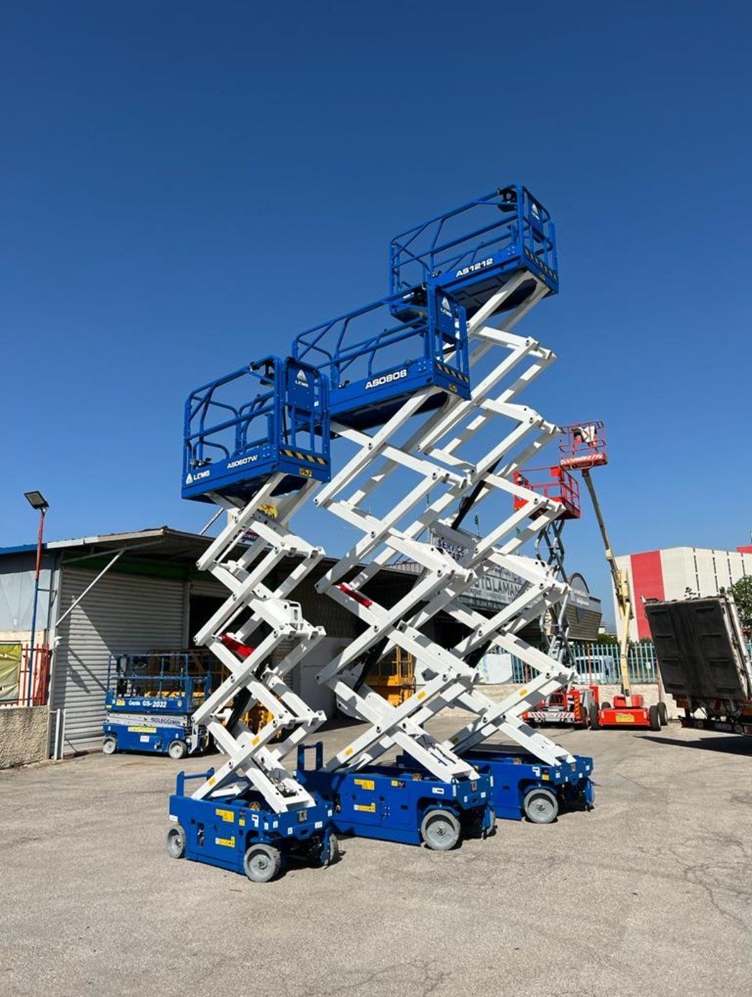 Tre piattaforme aeree blu e bianche all'aperto, sollevate contro un cielo azzurro.