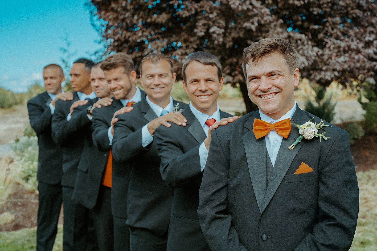 A groom and his groomsmen are posing for a picture.