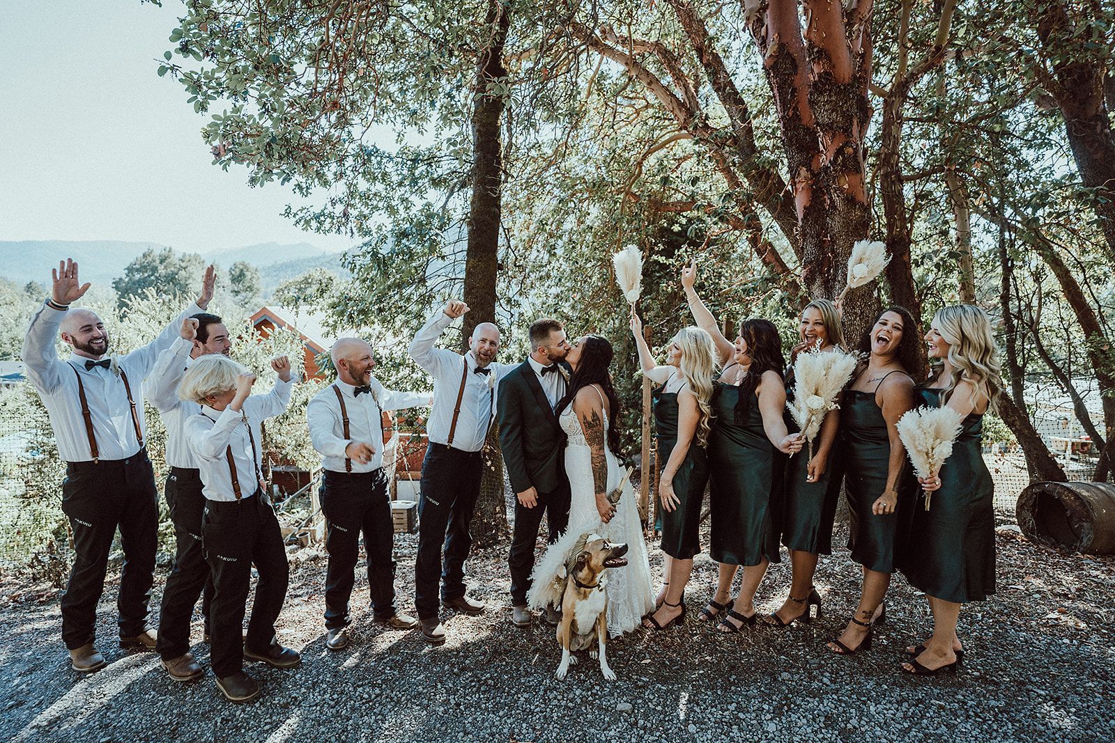 A bride and groom are posing for a picture with their wedding party and a dog.