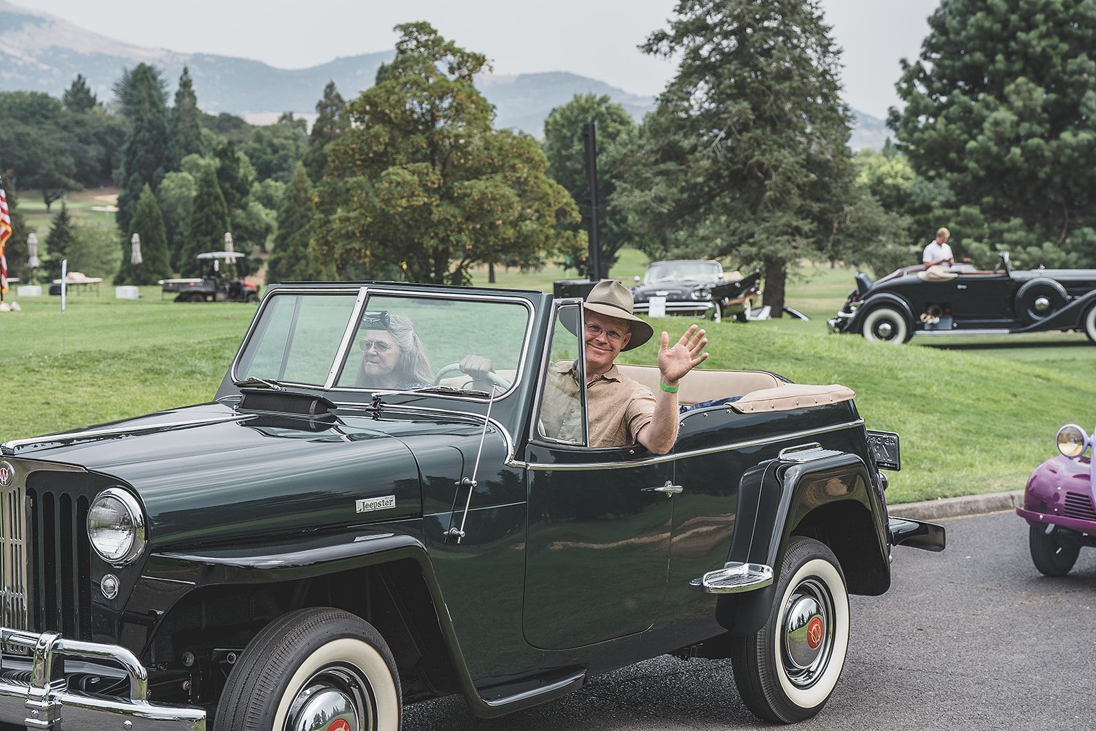 A man in a hat is driving a black jeep