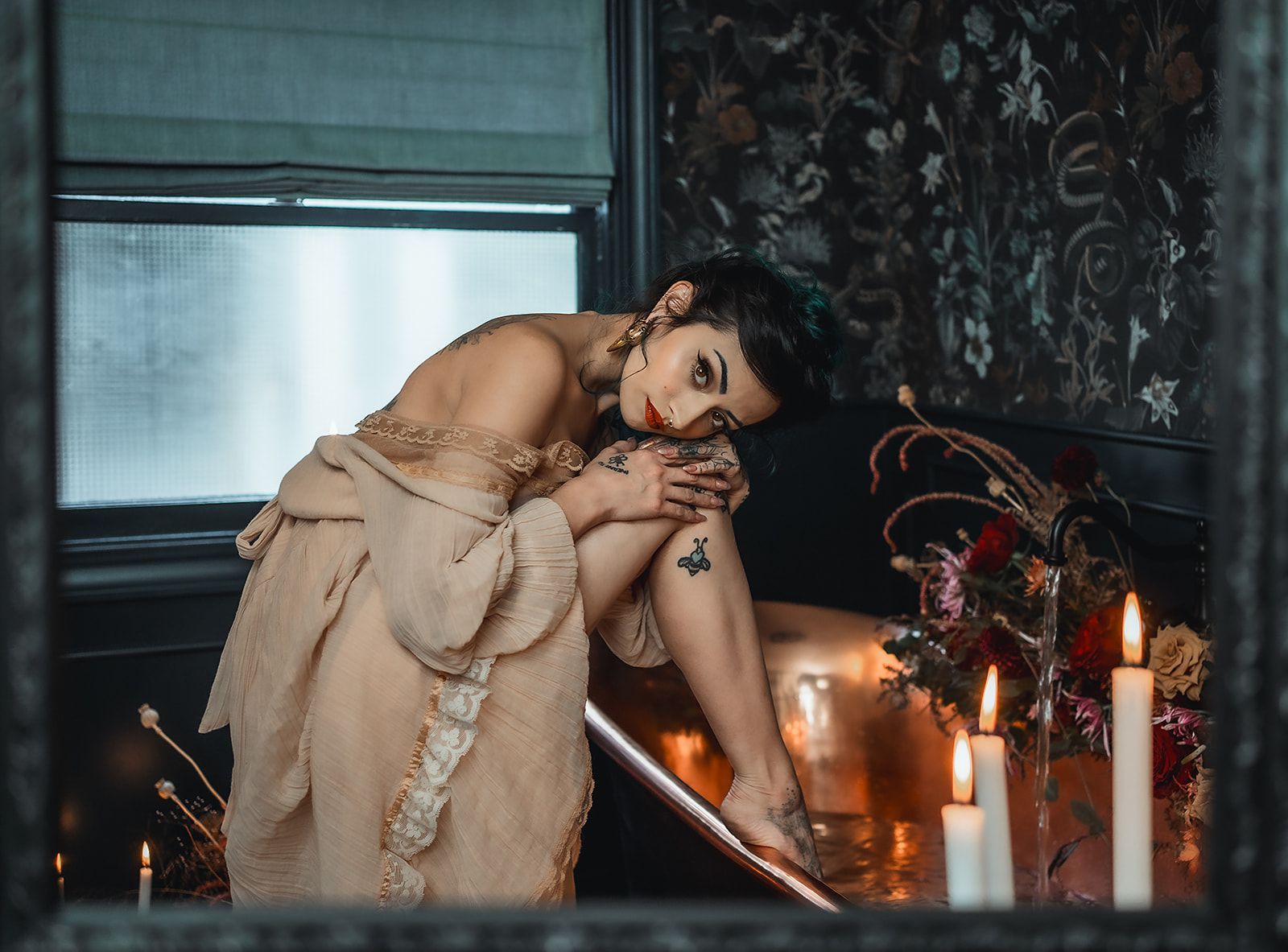 A woman is sitting in a bathtub surrounded by candles.