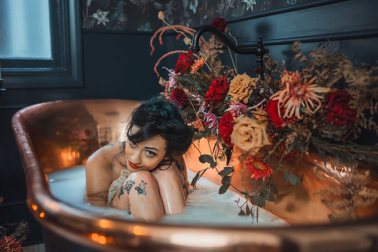 A woman is laying in a bathtub filled with milk and flowers.