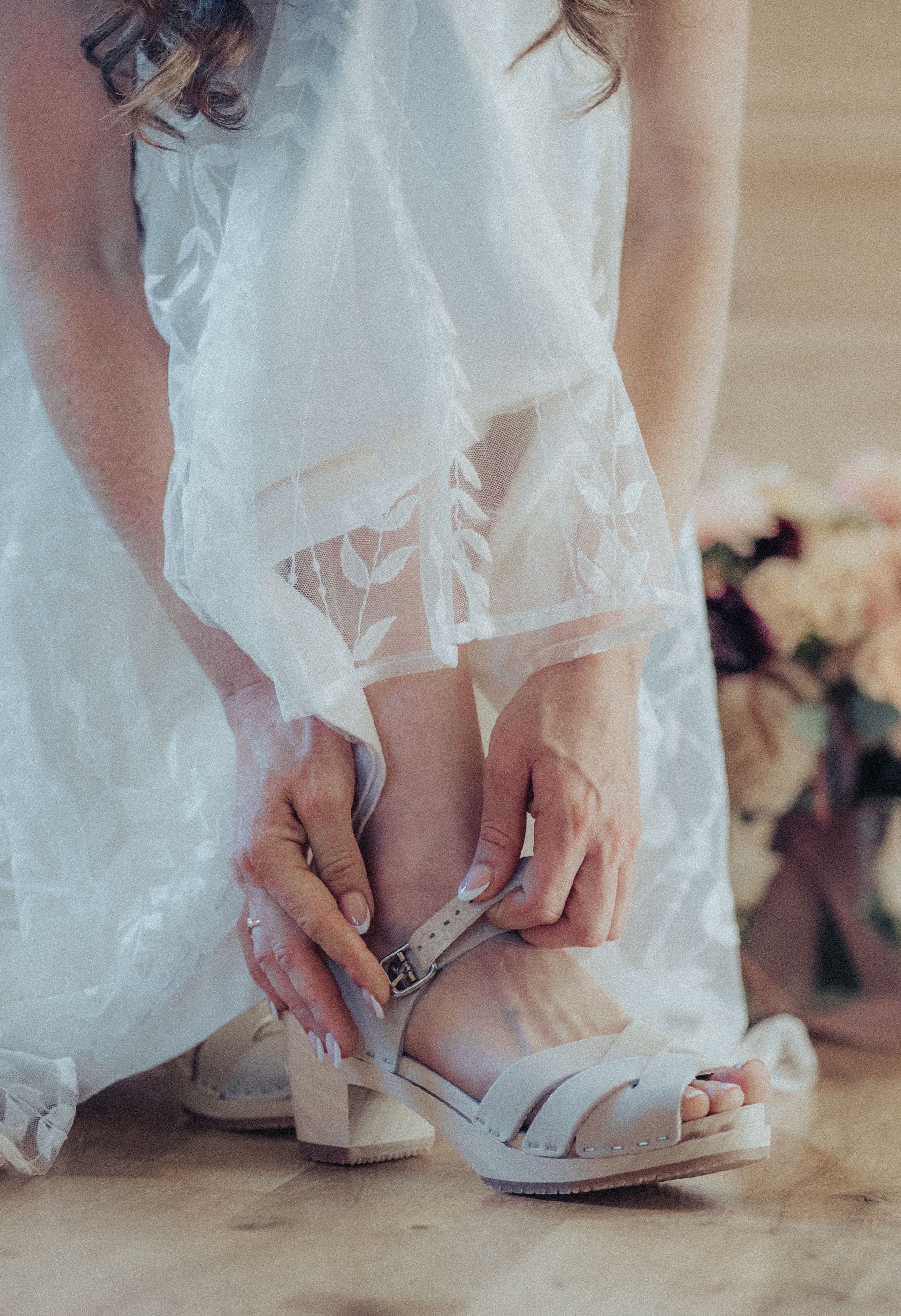 A woman in a white dress is tying her shoes.