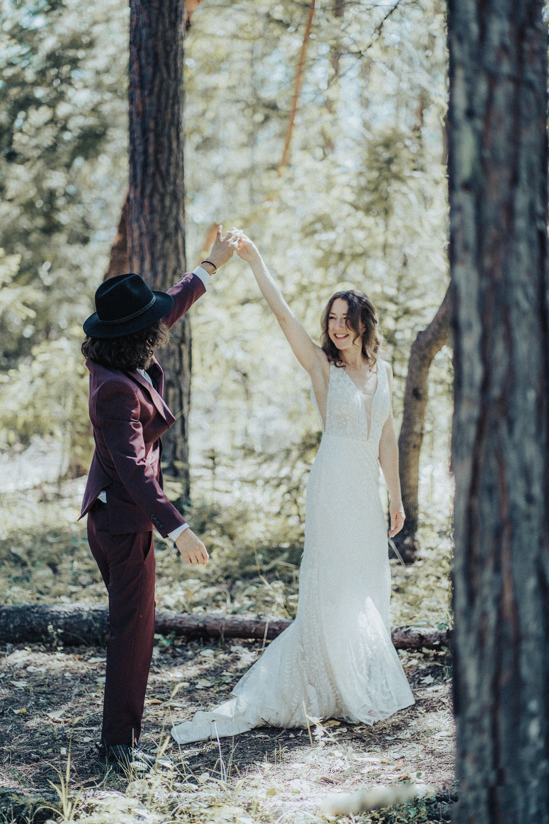 A bride and groom are dancing in the woods.