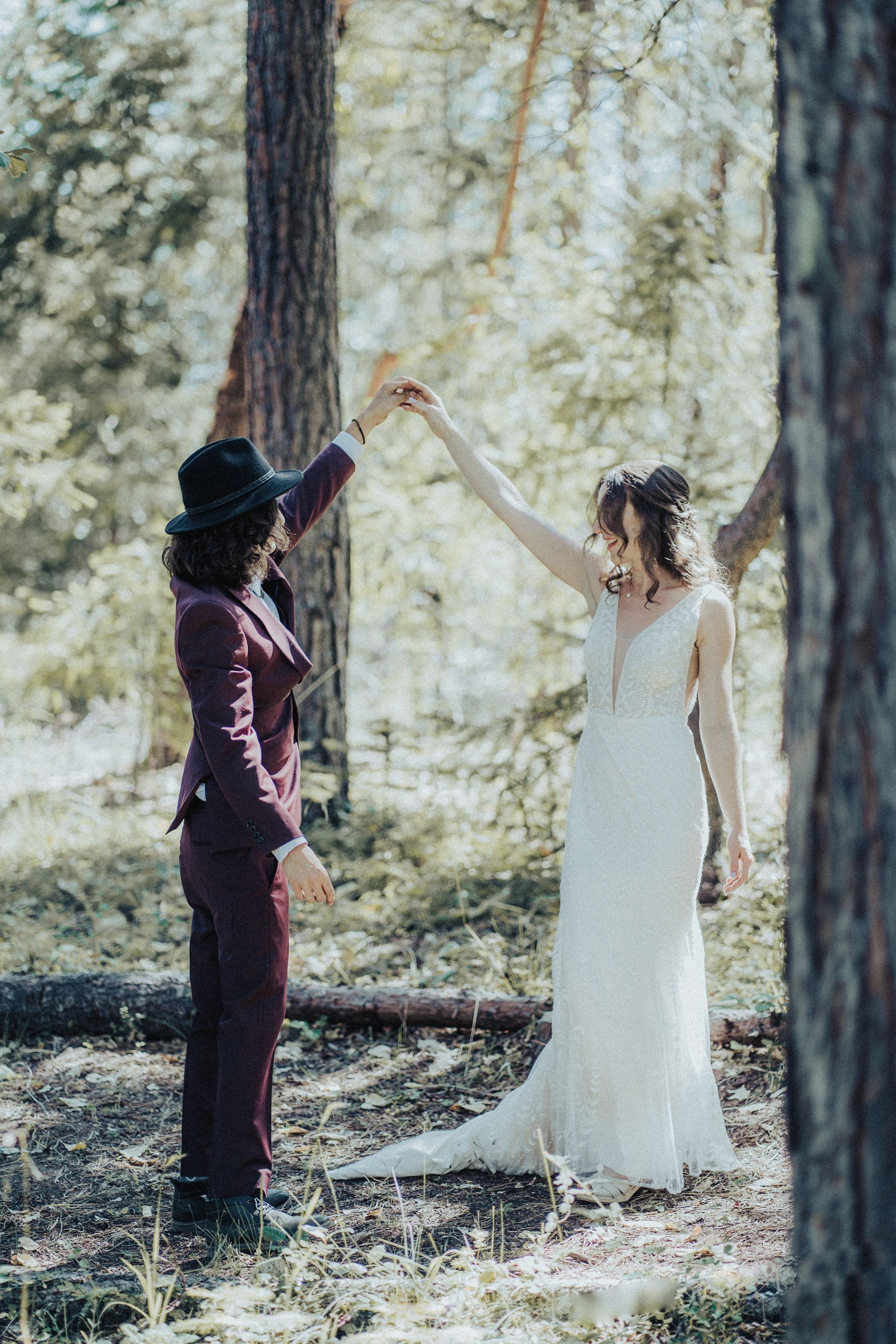 A bride and groom are dancing in the woods.
