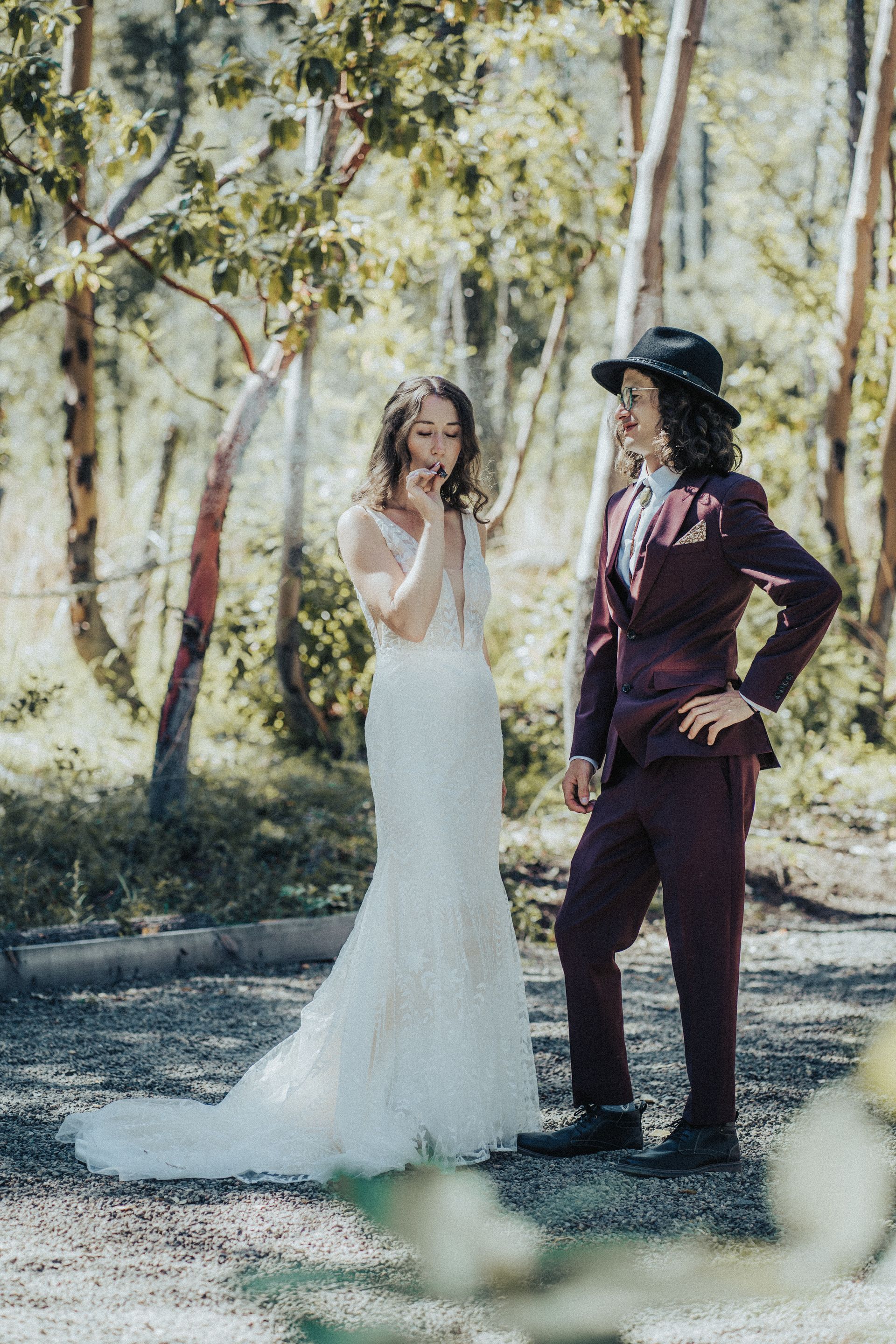 A bride and groom are standing next to each other in the woods.