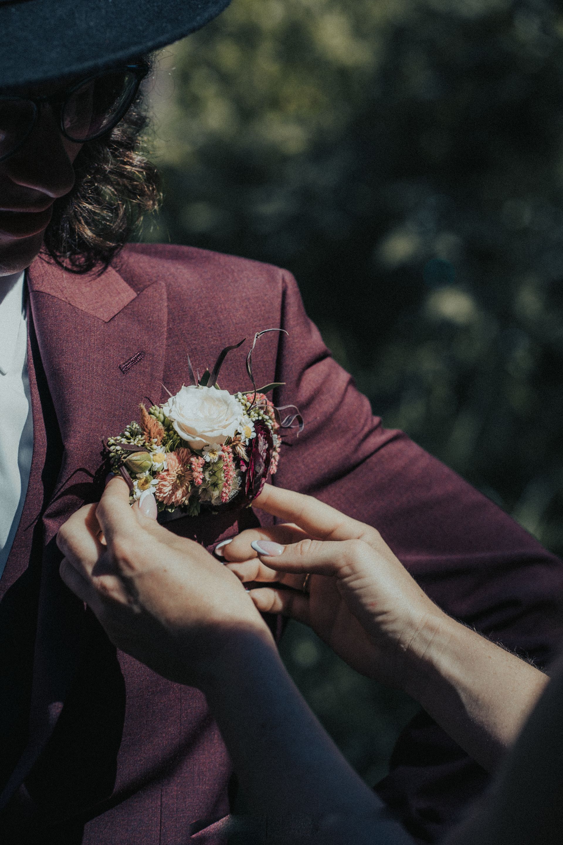 A man in a suit is getting a bouquet of flowers from a woman.