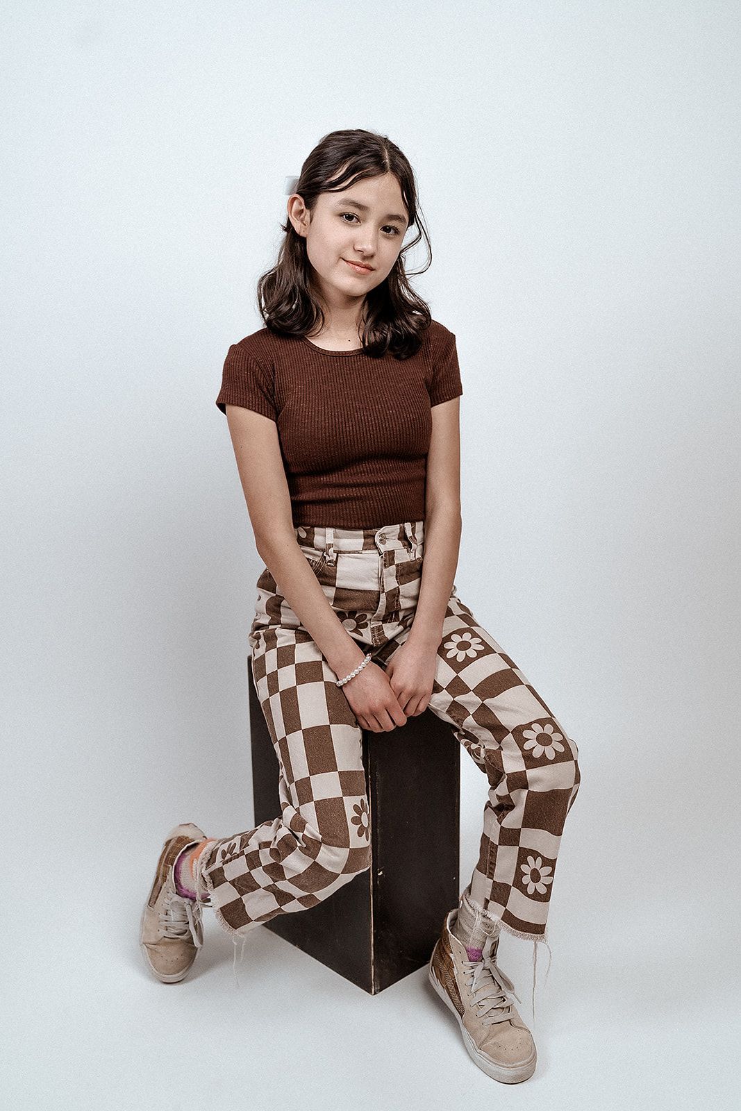 A young girl is sitting on a wooden box.