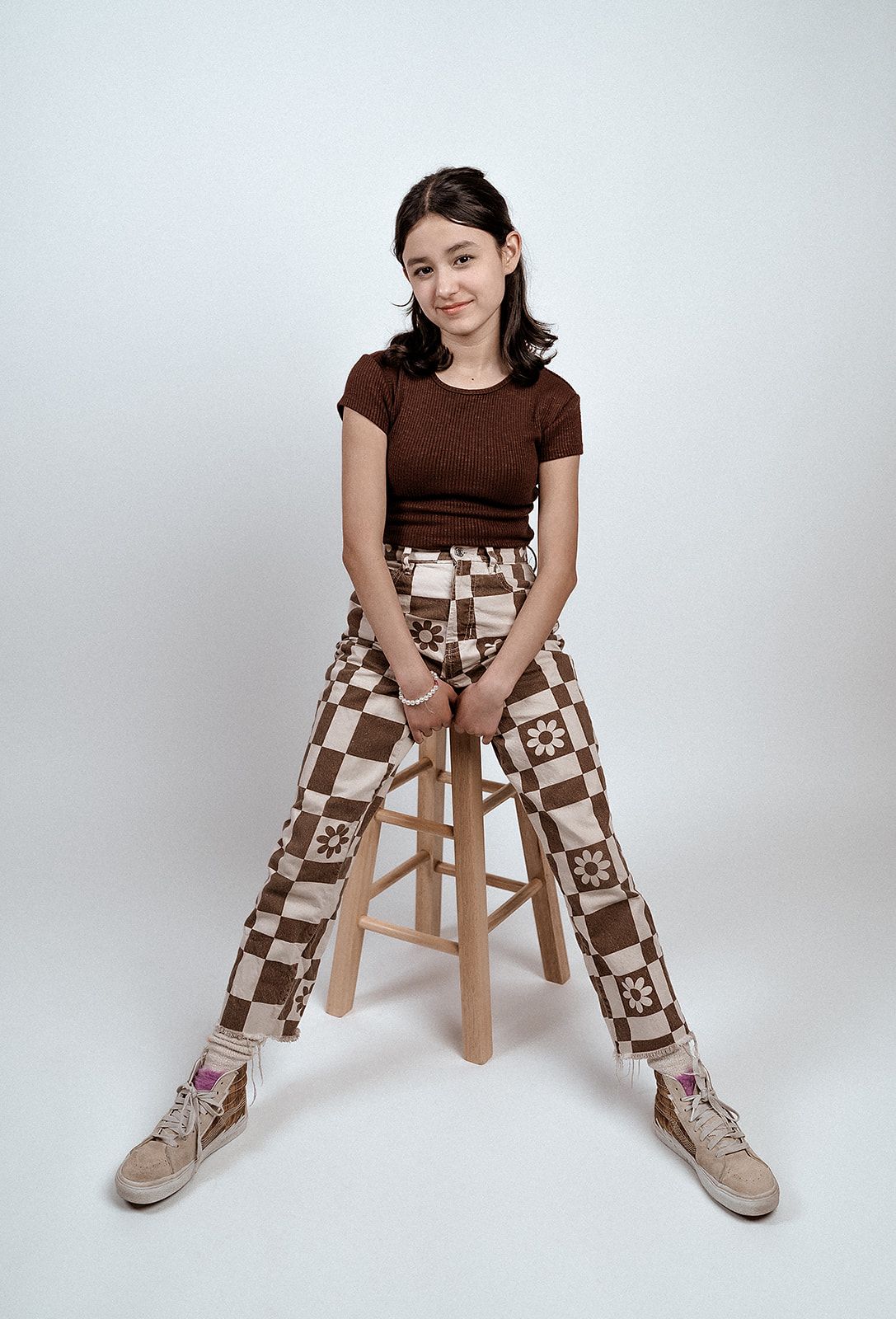 A young girl is sitting on a wooden stool.